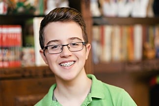 Teenage boy with glasses and braces smiling